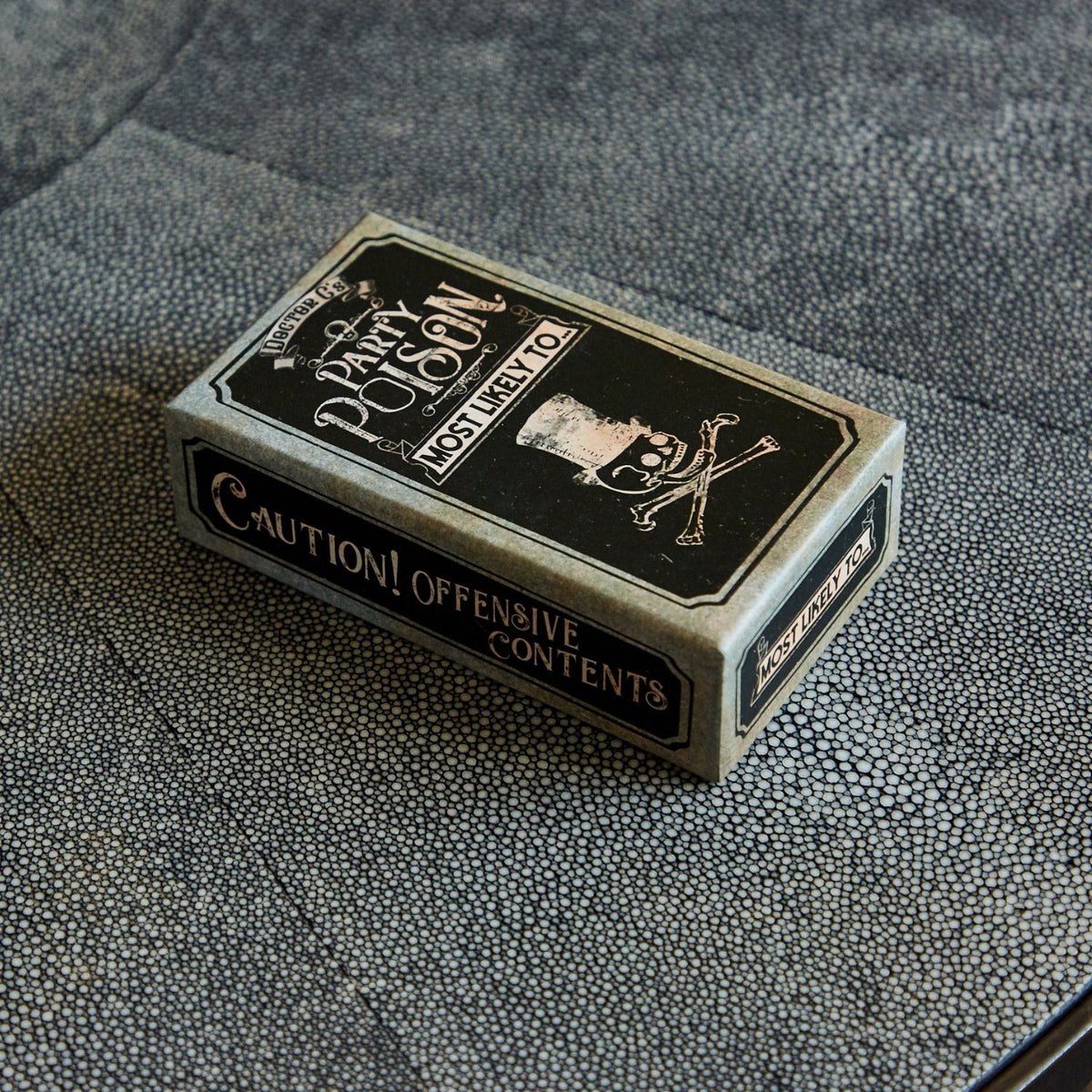 Playing card box labeled &#39;Party Poison&#39; on a textured surface
