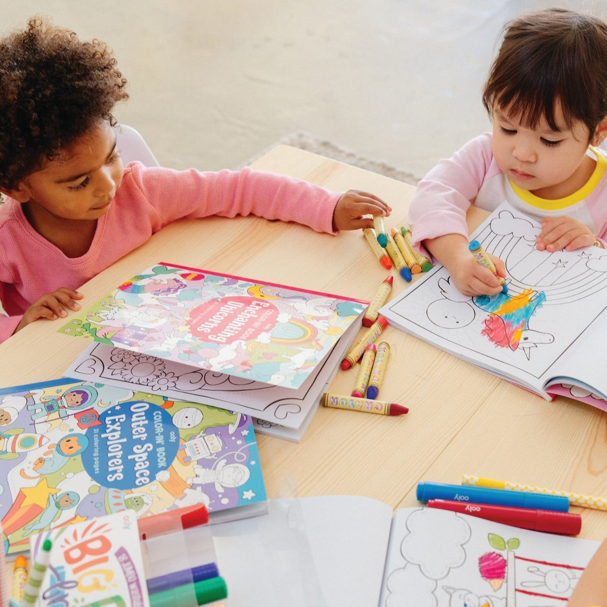 two kids colouring in the book using crayons 
