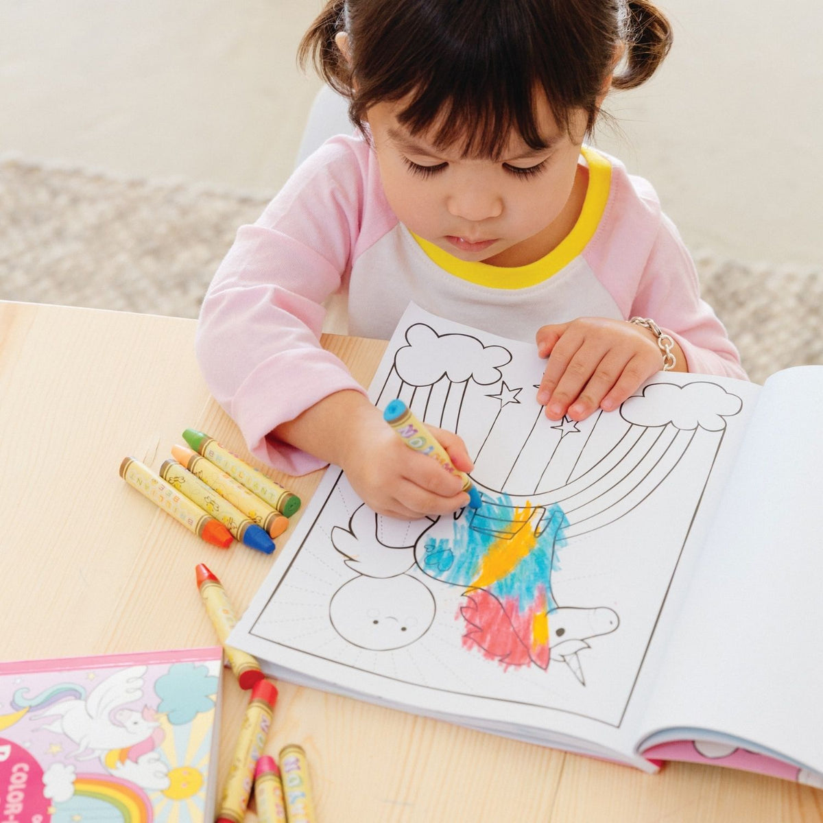 a girl colouring in the book using crayons 