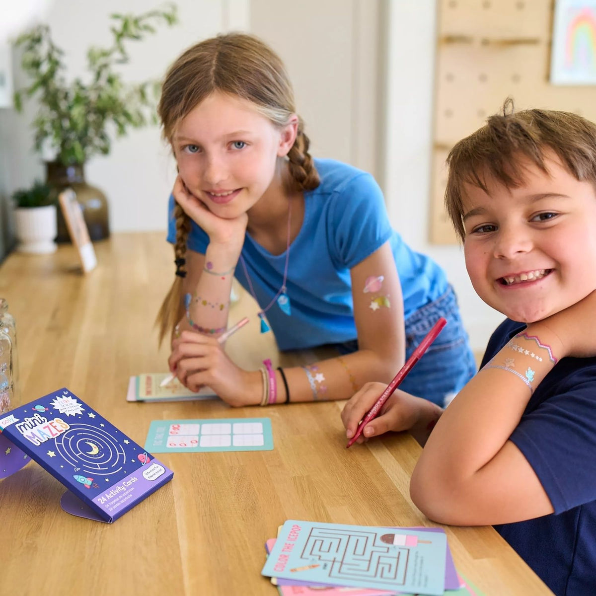 two kids drawing in the Mini Mazes Activity Cards featuring space-themed illustrations with rockets and planets, 