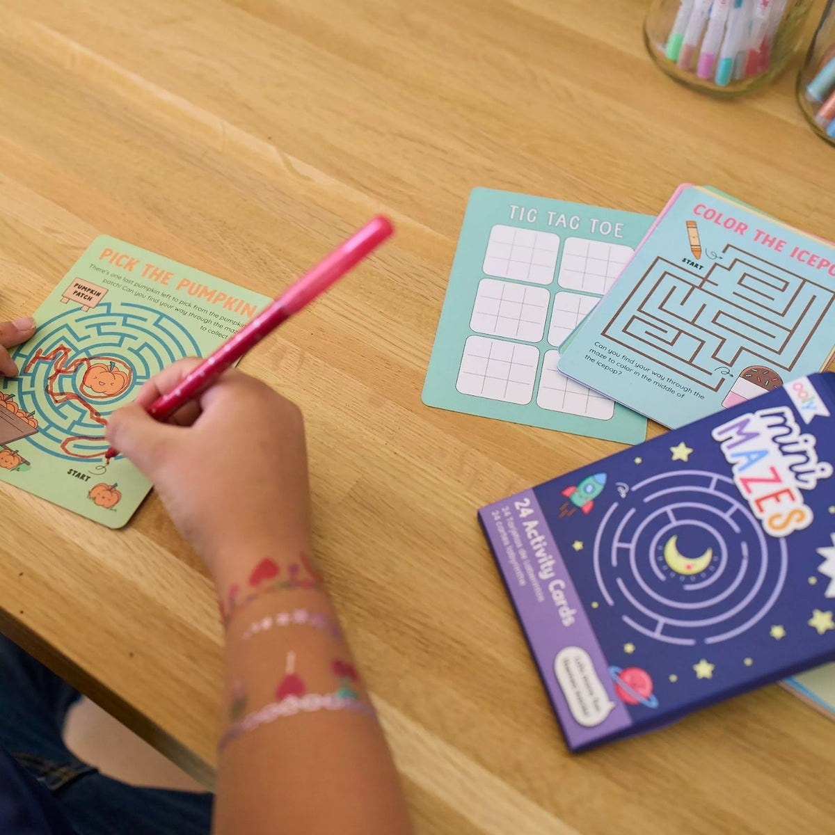 two kids drawing in the Mini Mazes Activity Cards featuring space-themed illustrations with rockets and planets, 