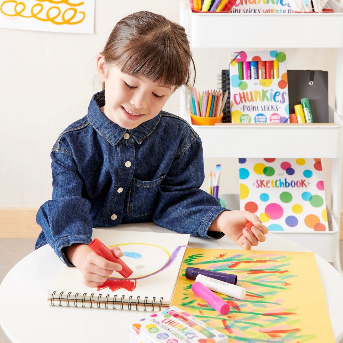 a girl drawing at a table using chunkies