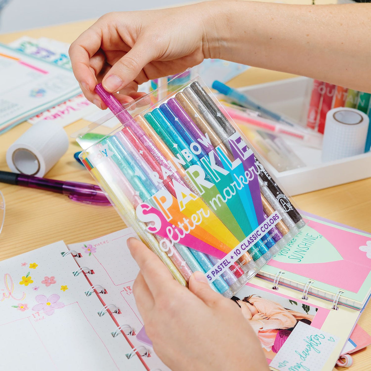 Kids holding a packet ofrainbow sparkle glitter markers in various colors