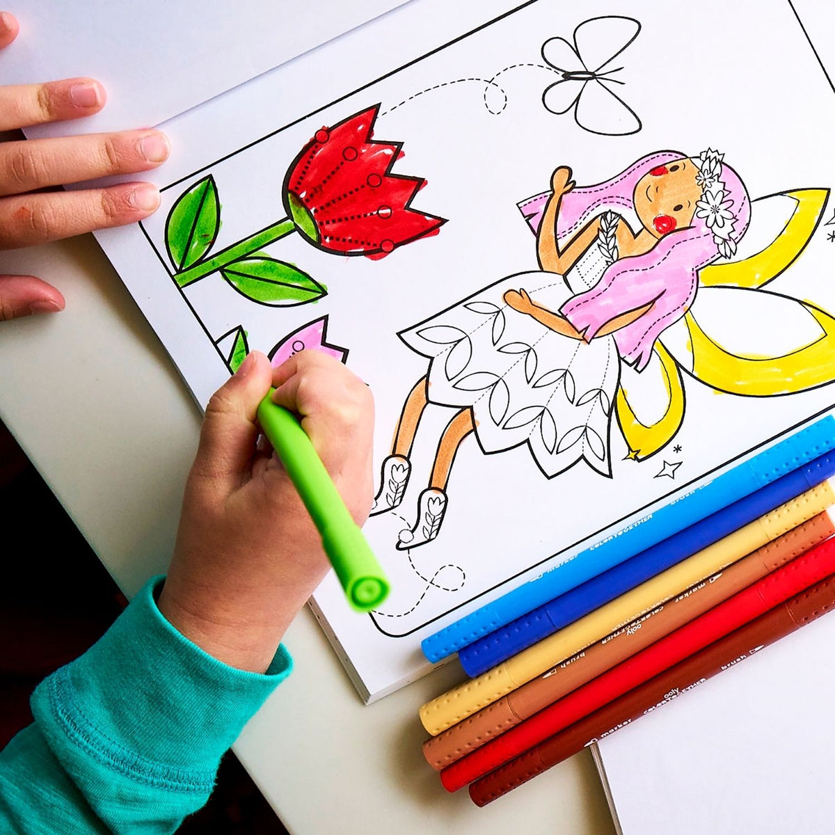 a kid drawing in a colouring book using the colour together markers