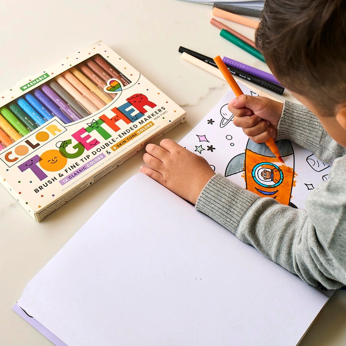 a kid drawing in a colouring book using the colour together markers