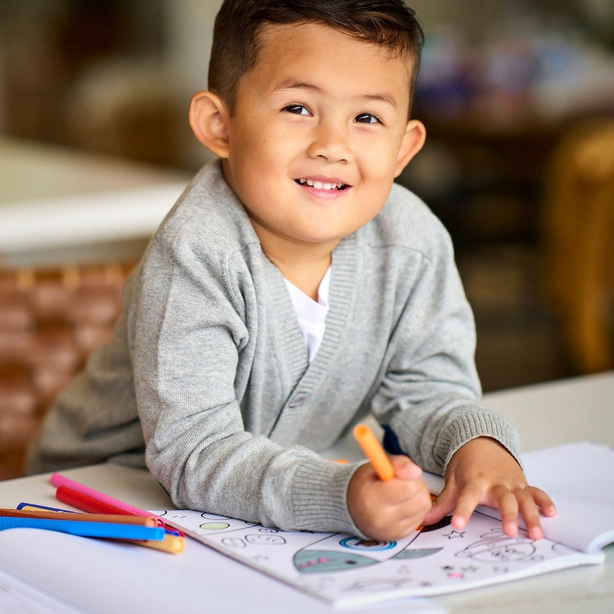 a kid drawing in a colouring book using the colour together markers