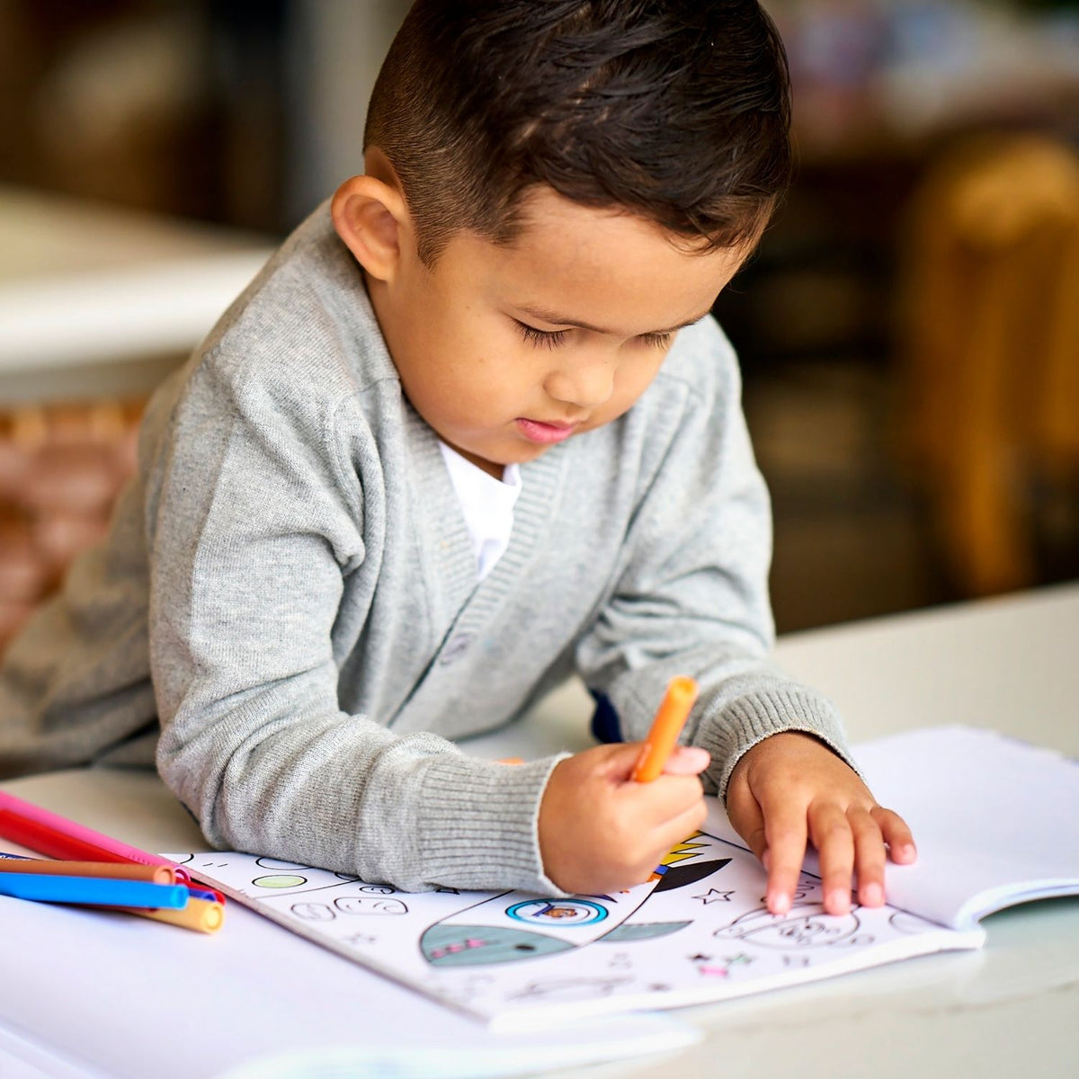 a kid drawing in a colouring book using the colour together markers