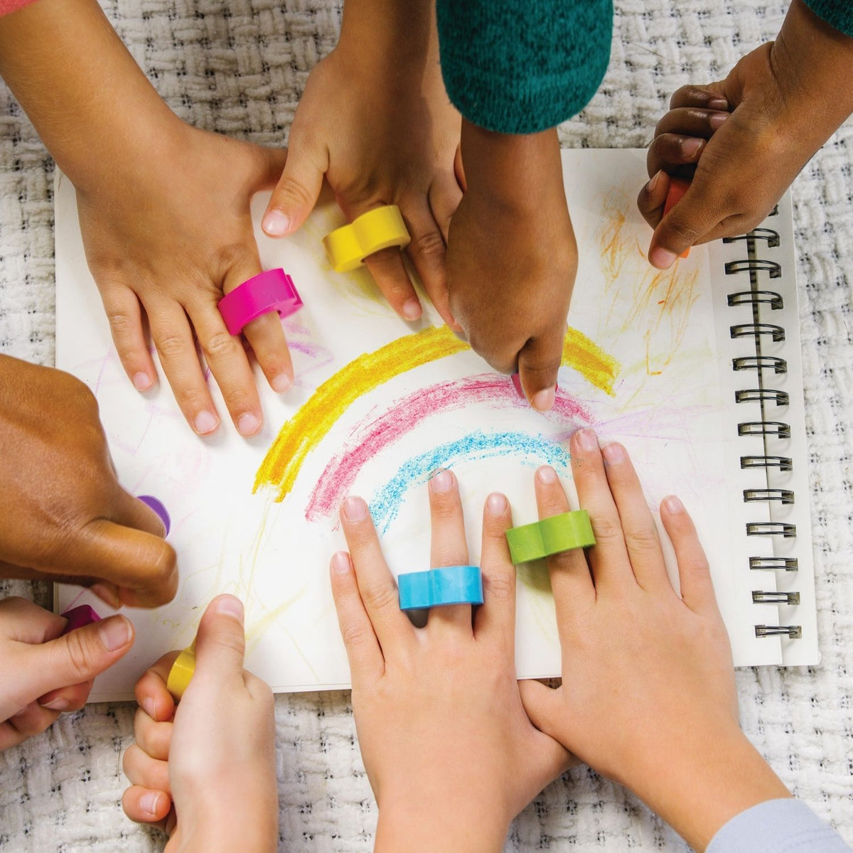 kids drawing with six heart-shaped ring crayons in rainbow colors,