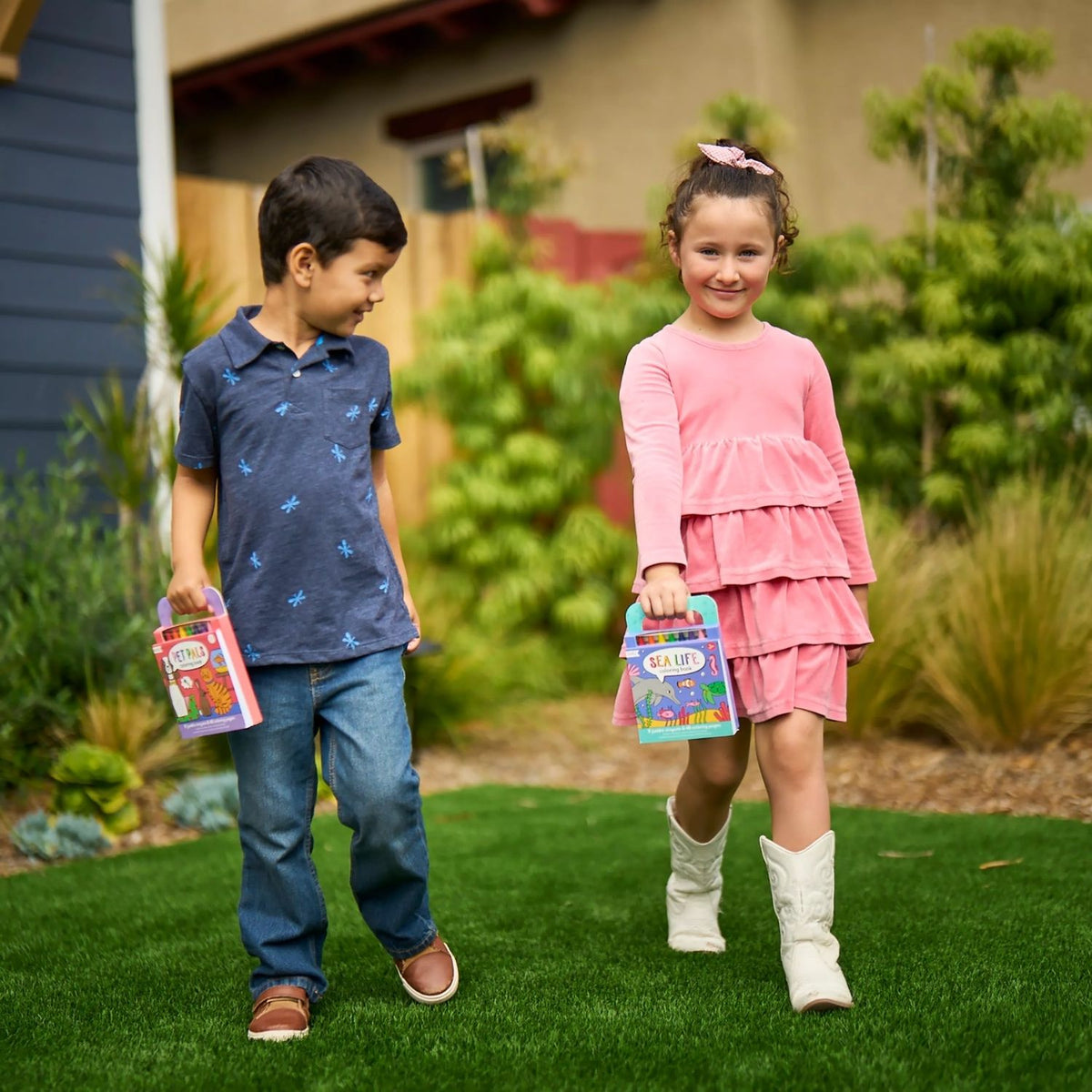 a girl and boy in garden carrying Carry Along Crayon Book each