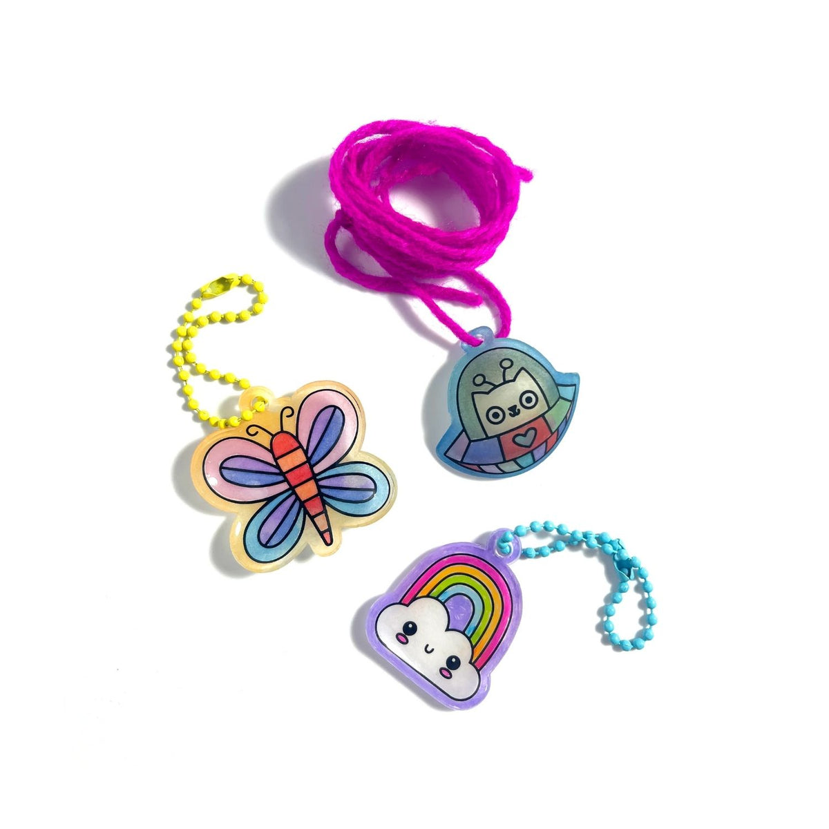Samples of Shrink-Its! DIY Shrink Art Kit featuring colorful butterfly, rainbow charms on chains