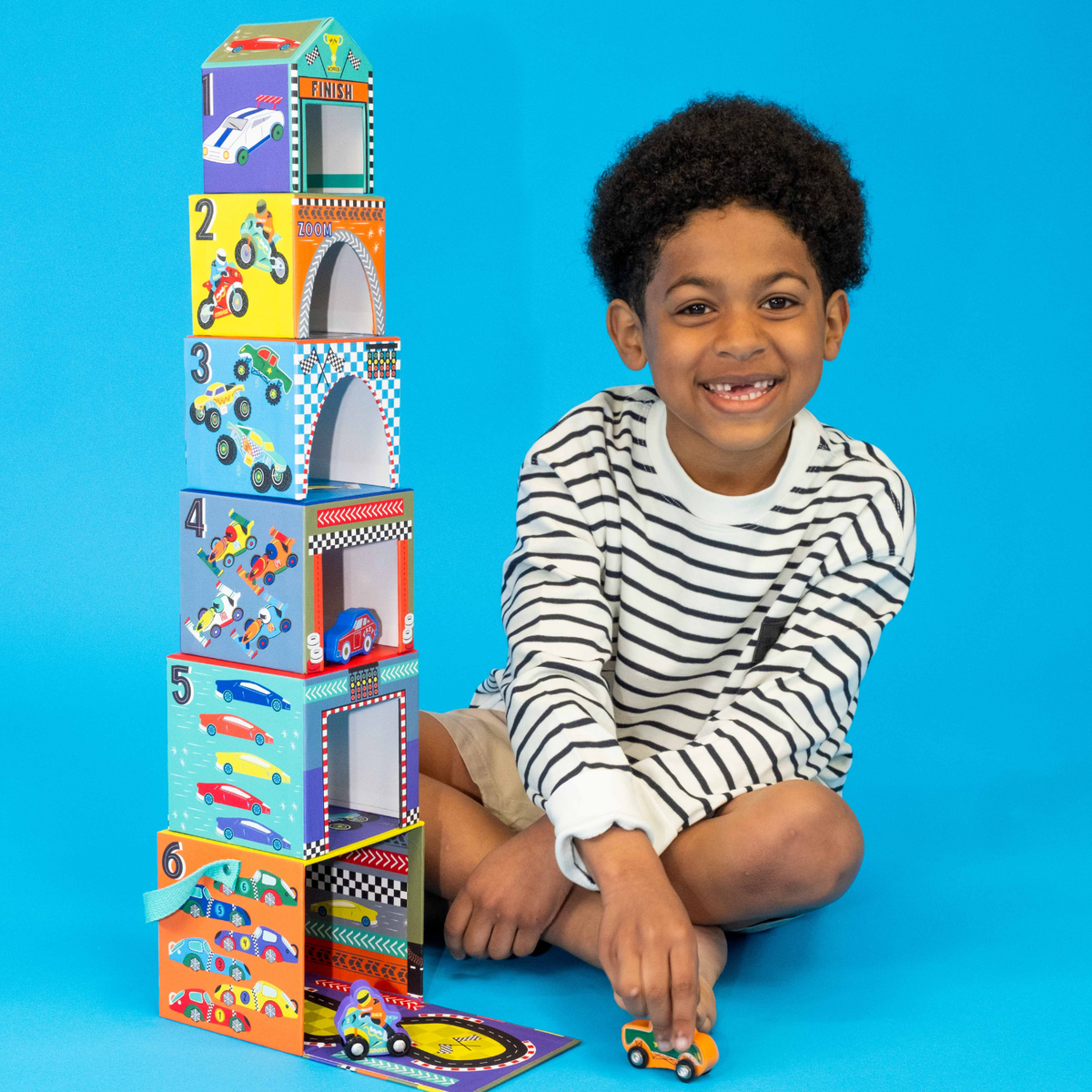A boy sitting next to the construction stack and play 