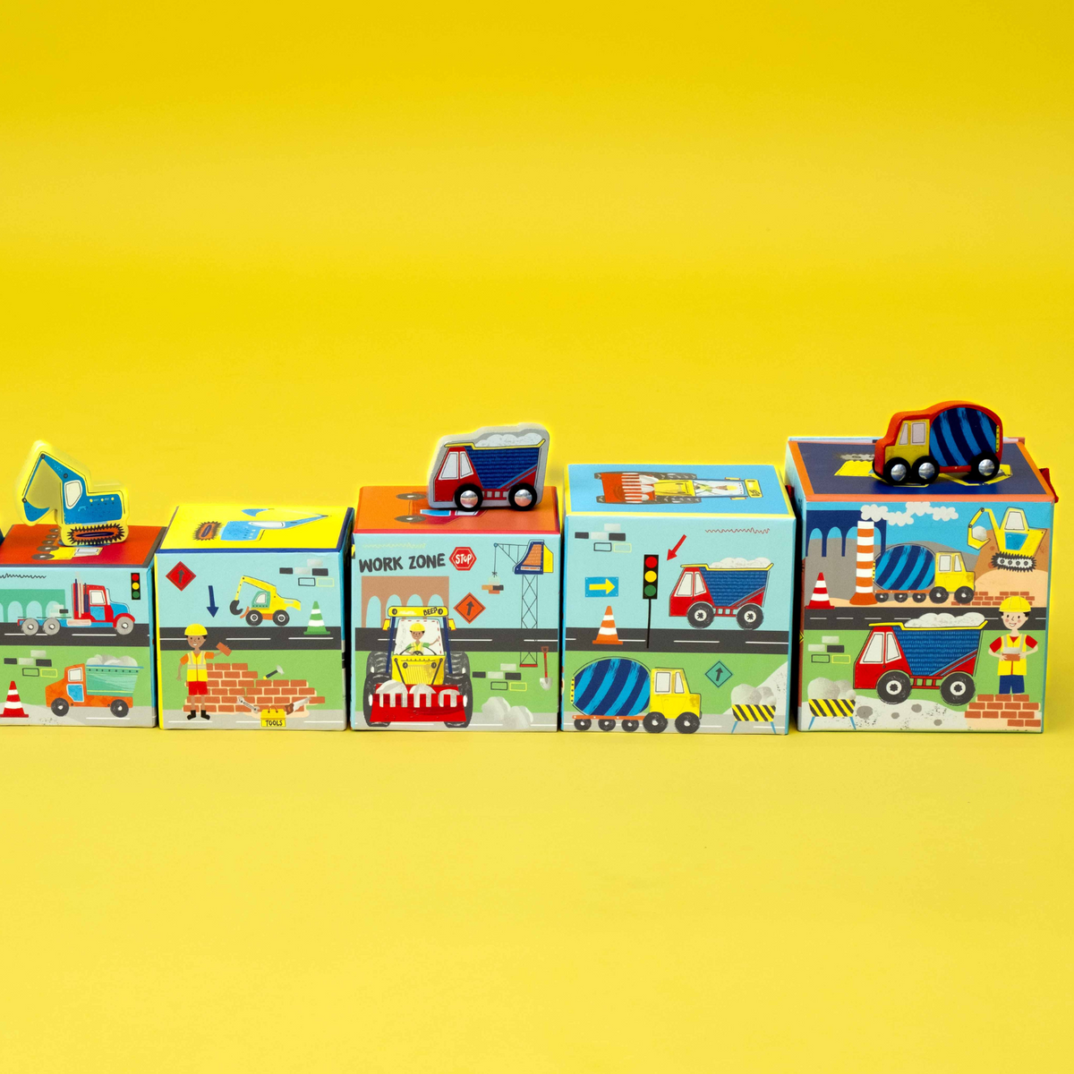 A colorful box with a carry handle, labeled &#39;Stack &amp; Play&#39;, featuring images of construction vehicles like diggers and trucks.