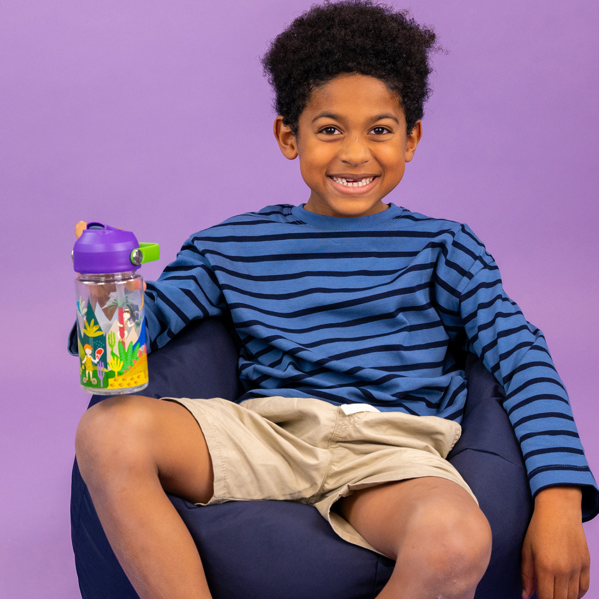 a boy holding A 450ml Tritan drinks bottle with a dinosaur print design, featuring a purple carry handle and spout, and an extra straw.