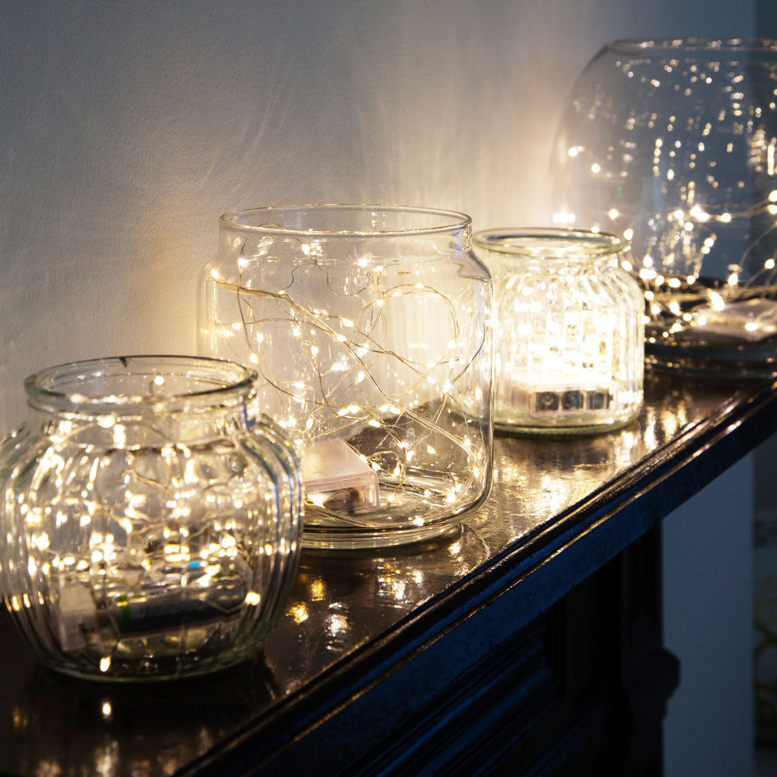 Botanical Mistletoe Bead String Lights in glass jars on a fireplace mantle