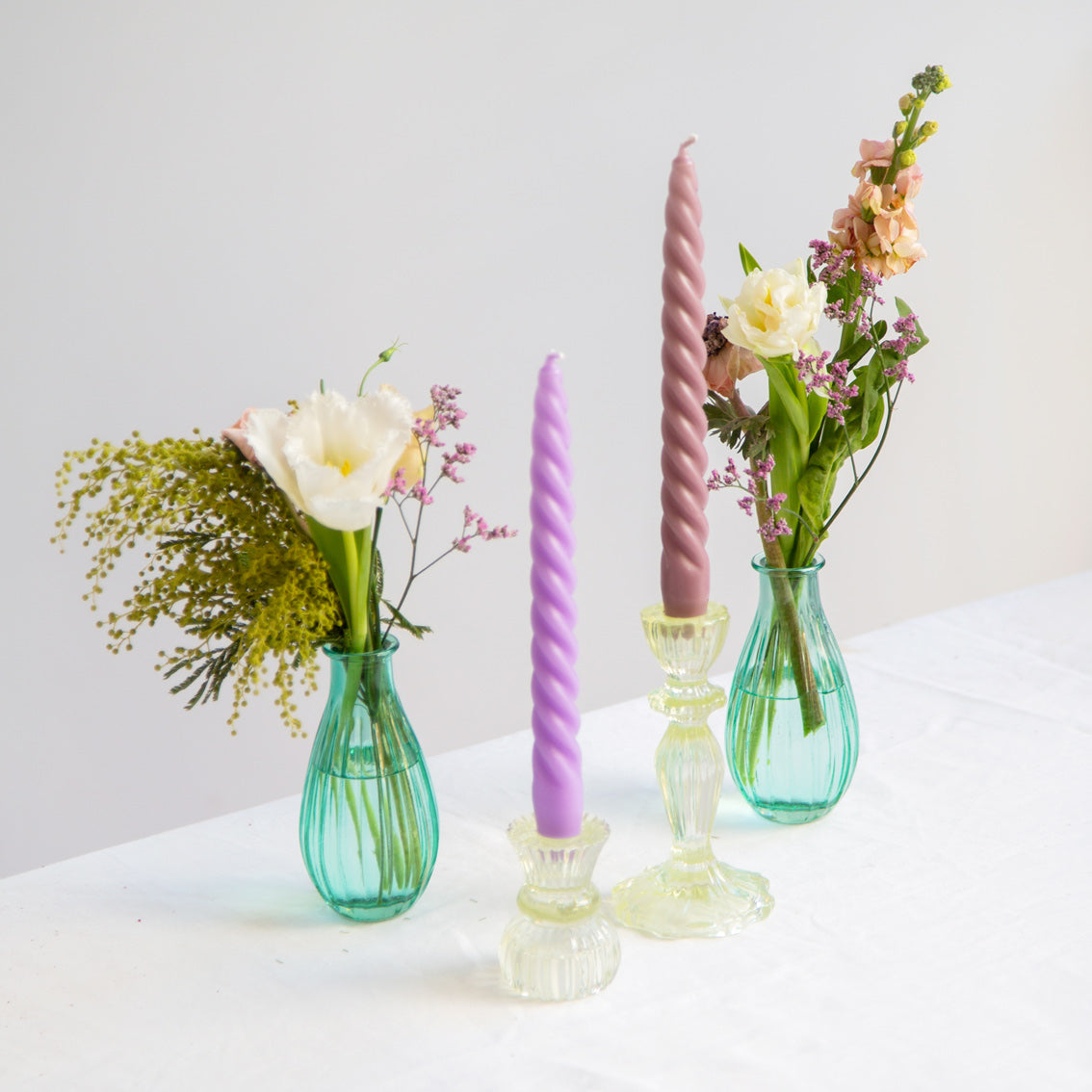 lilic and soft pink Spiral Candles in yellow glass candle holders on a table