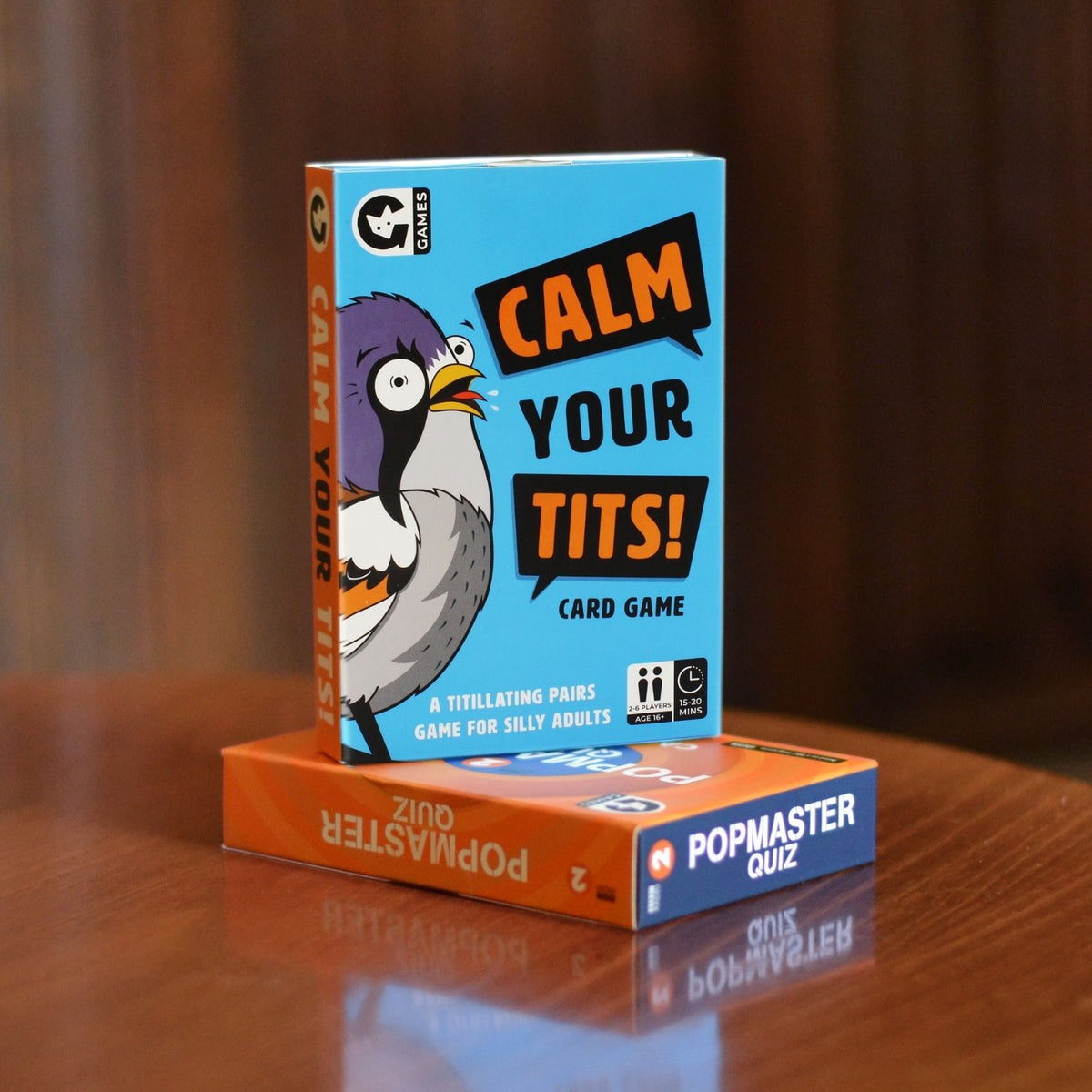 The image shows a box of the &#39;Calm Your Tits&#39; card game featuring a cartoon bird with exaggerated expression on a blue background. The game is indicated for 2-6 players, ages 16+, with 48 cards.