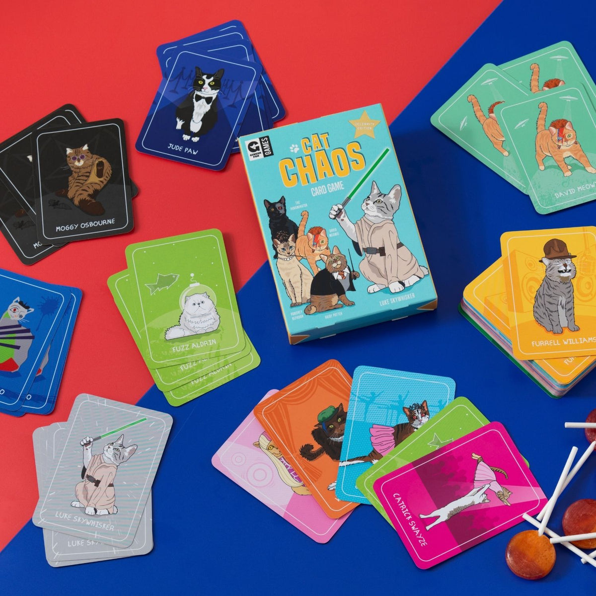 The image features the packaging of the card game &quot;Cat Chaos.&quot; It displays a vibrant blue background with illustrations of four different breeds of cats dressed in various costumes, including a Sphynx in a bat costume, a Persian in a tuxedo, a British Shorthair in a chef&#39;s outfit, and a Domestic Shorthair in a business suit.