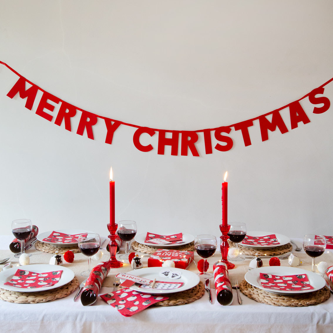 Merry Christmas Glitter Garland hanging on a wall above a christmas table