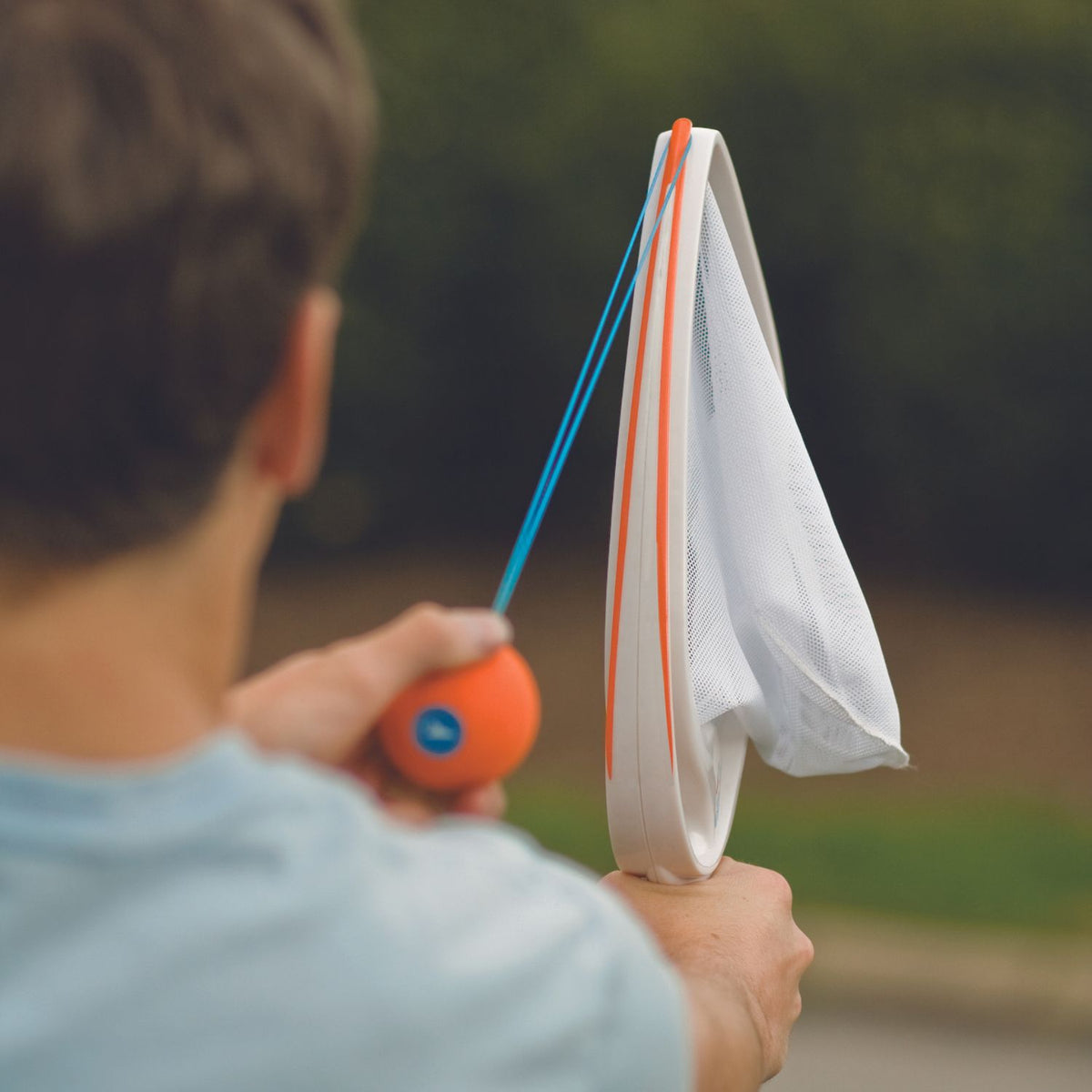 A close-up focus on a player's hand hooking the durable elastic loop of the ball over the specialised launching hook on the racket.