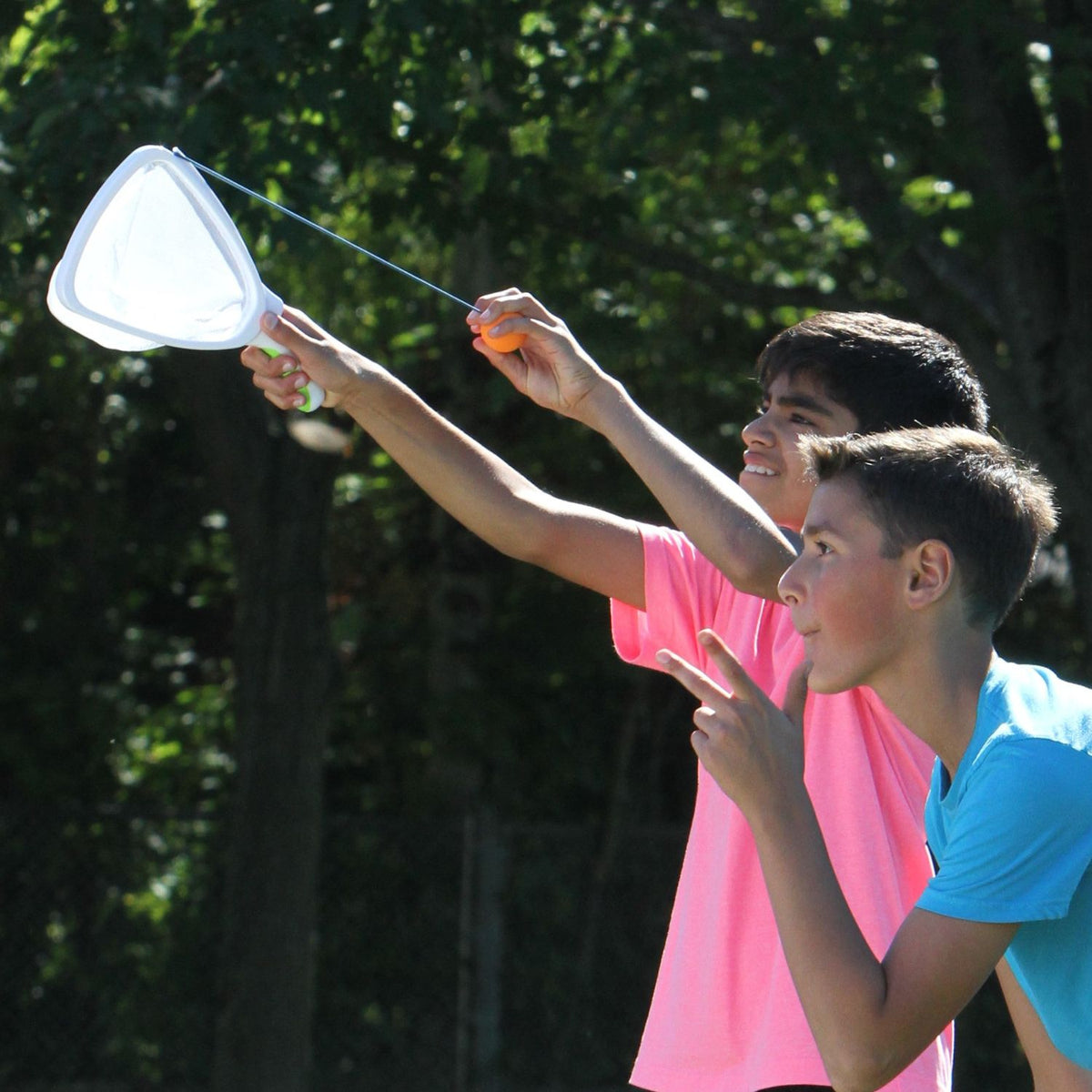 Two children outdoors, one holding a Slingball net