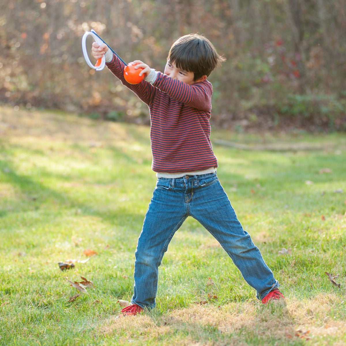 Child shooting a Djubi ParaShoot in a grassy outdoor area
