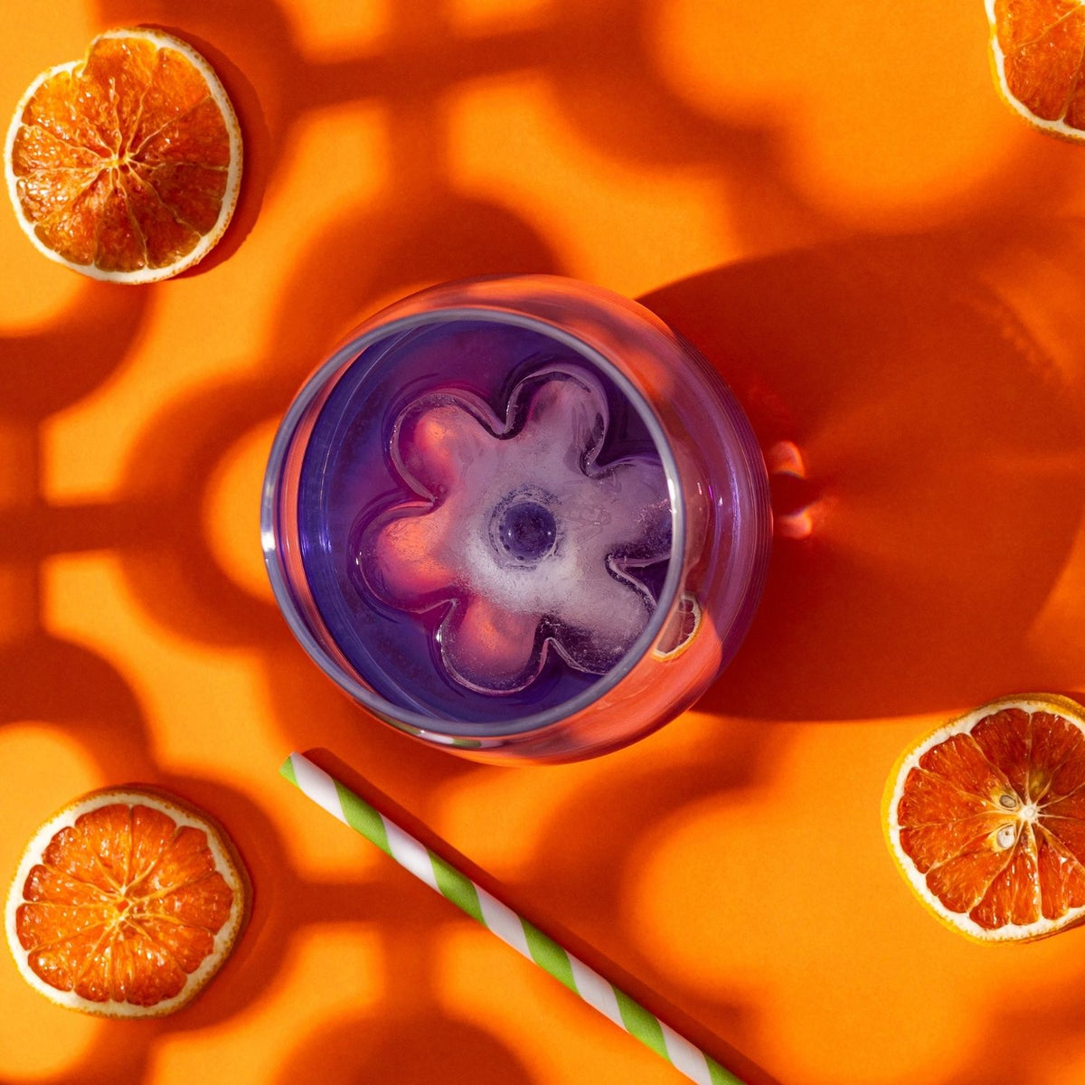 A retro-style cocktail glass featuring a large daisy ice cube, illustrating the "groovy" 70s aesthetic and premium beverage presentation.