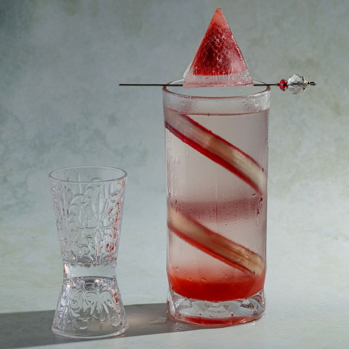 Cocktail with a strawberry pyramid ice cube garnish made with Charcoal-grey silicone pyramid ice mould featuring nine geometric cavities designed to create large, sharp-edged ice shapes for glassware.