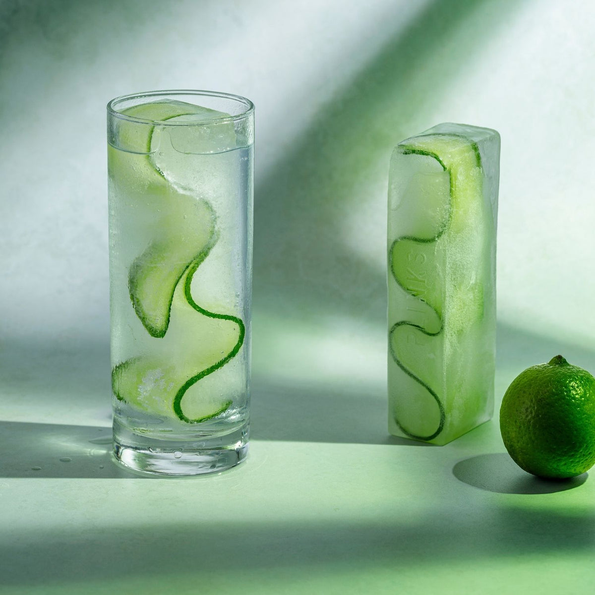 Two glasses with cucumber slices in ice slabs. Keep drinks cool all day with this durable silicone ice tray. Ideal for large glasses and water bottles.