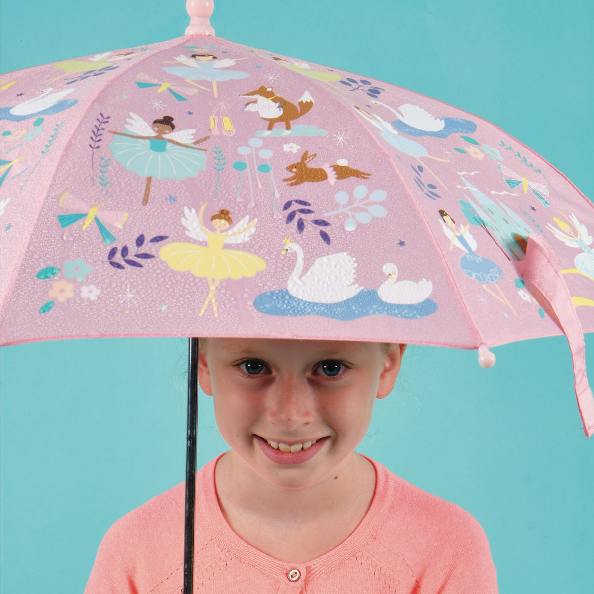 Child holding a pink umbrella with fairy and animal designs 