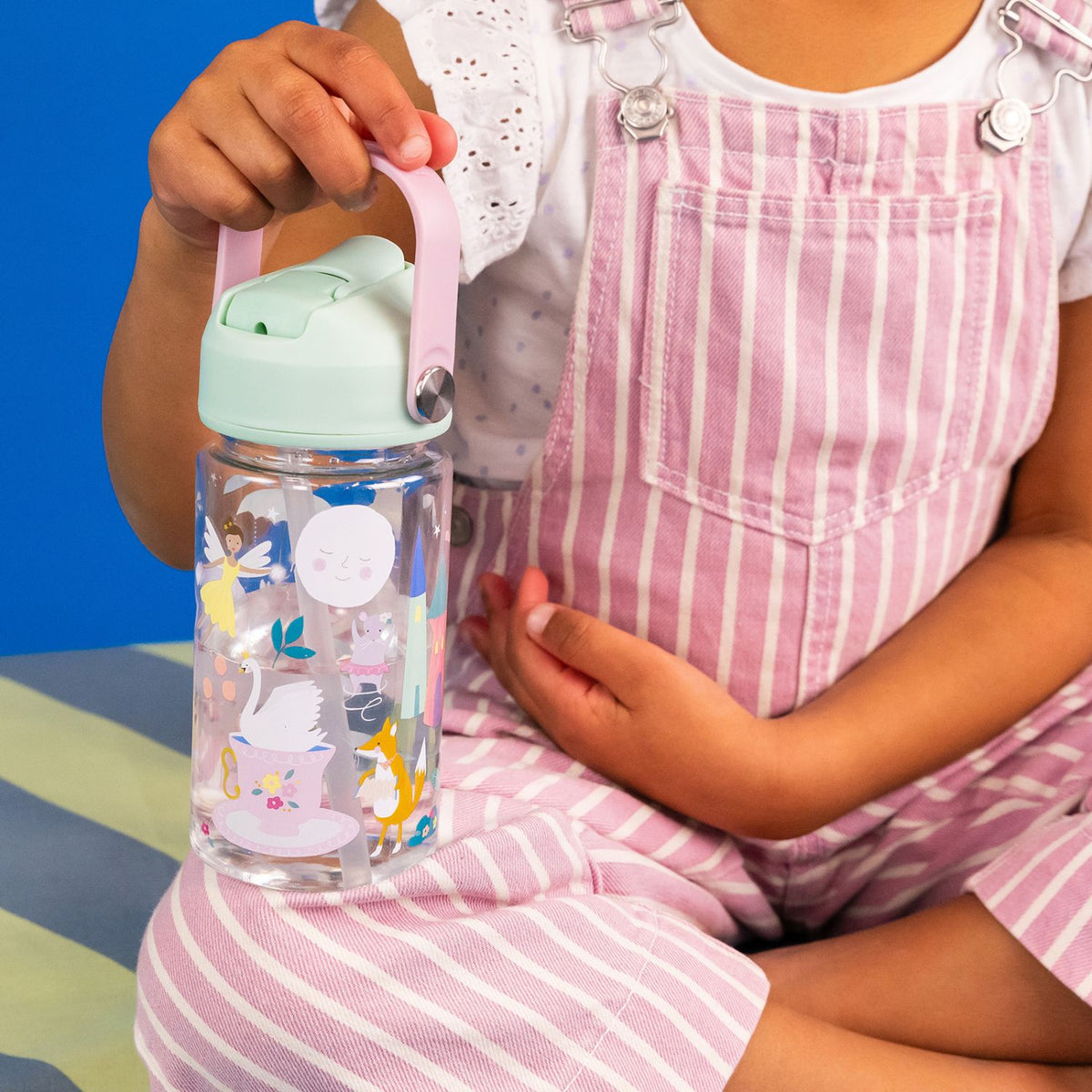 Child holding a colorful water bottle a with enchanted fairy design
