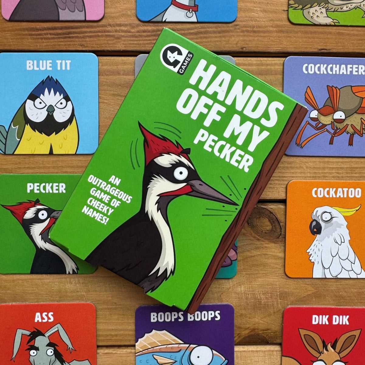 Card game titled 'Hands Off My Pecker' with colorful cards featuring animal illustrations on a wooden surface.