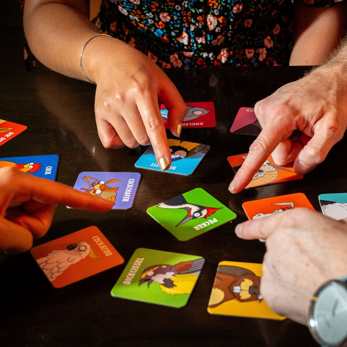People playing a card game with colorful cards on a table