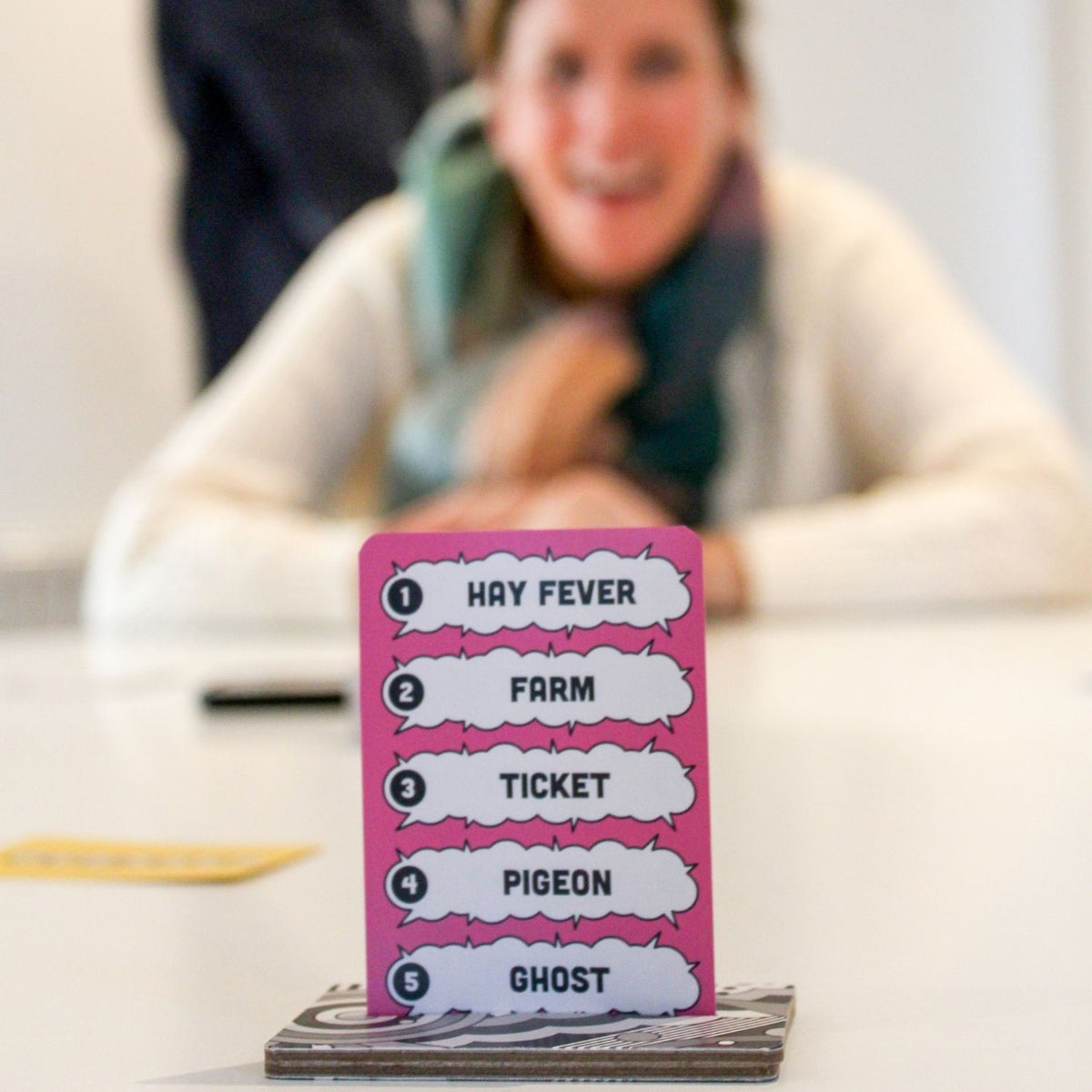 Pink Bangarang playing card with text in front of a blurred person sitting at a table