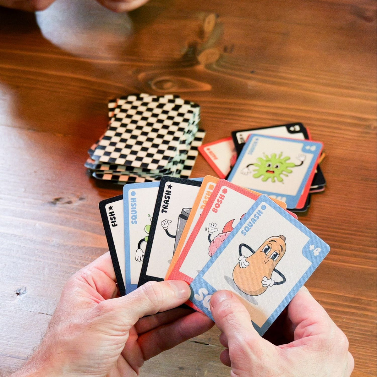 Hands holding cartoon-themed playing cards on a wooden table