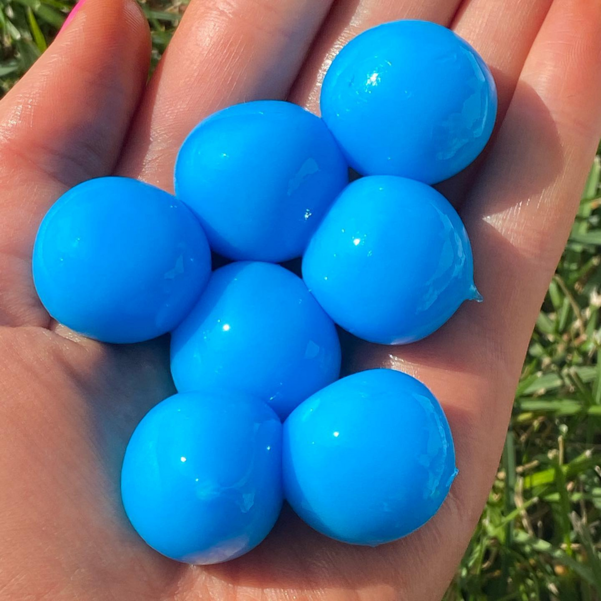 a hand holding blue throwable paintballs 