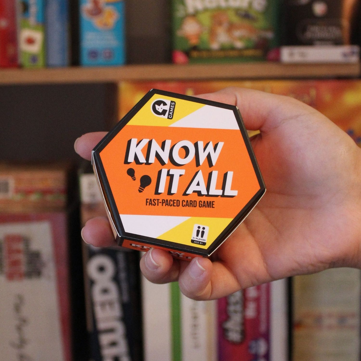 A trivia card game titled &#39;Know it All&#39; with a fast-paced card game description, featuring an orange and yellow color scheme with a hexagonal board game piece.