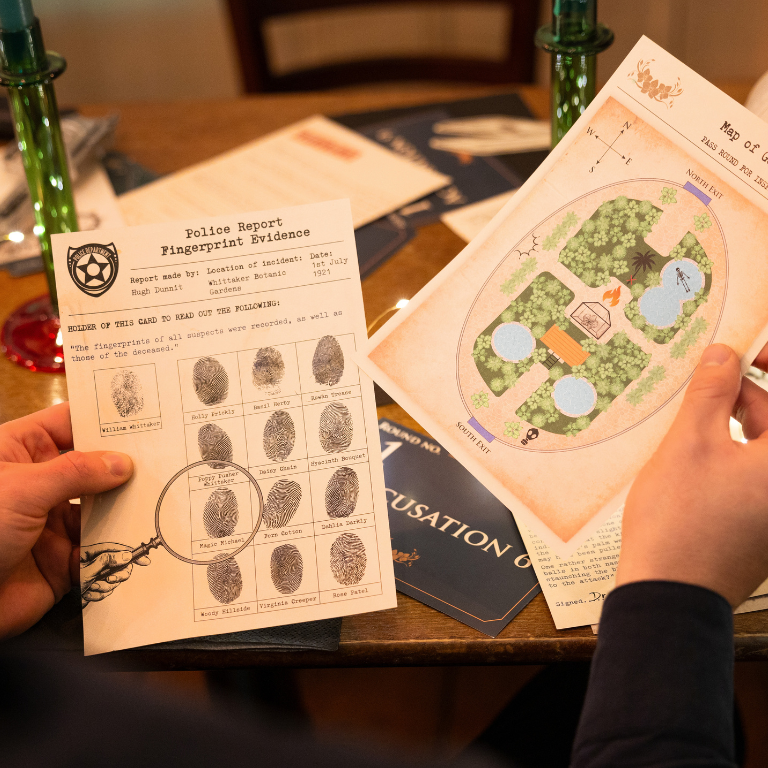Two hands holding a fingerprint evidence sheet and a map on a table with a warm glow for a murder mystery game