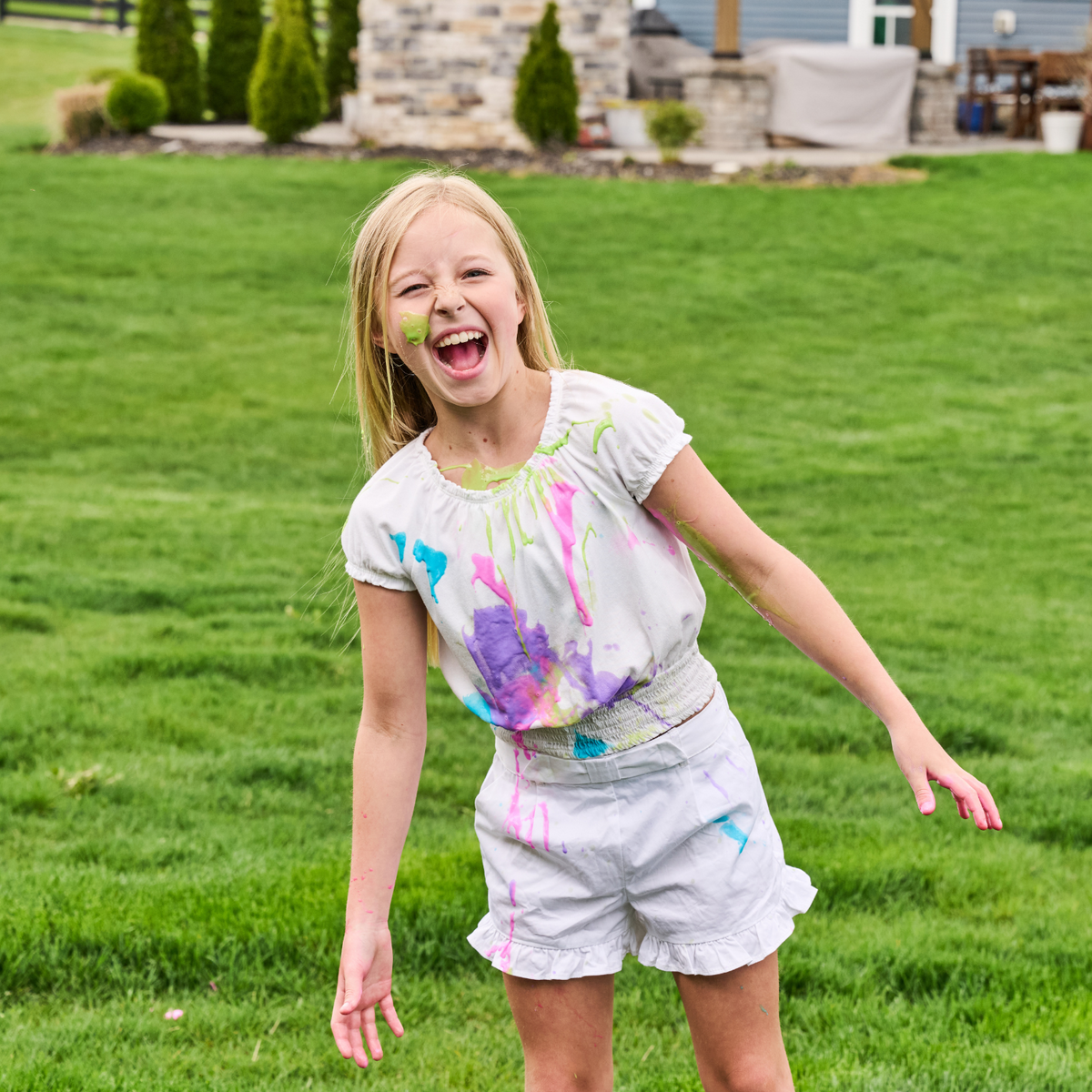 a girl outside wearing white and covered in paint