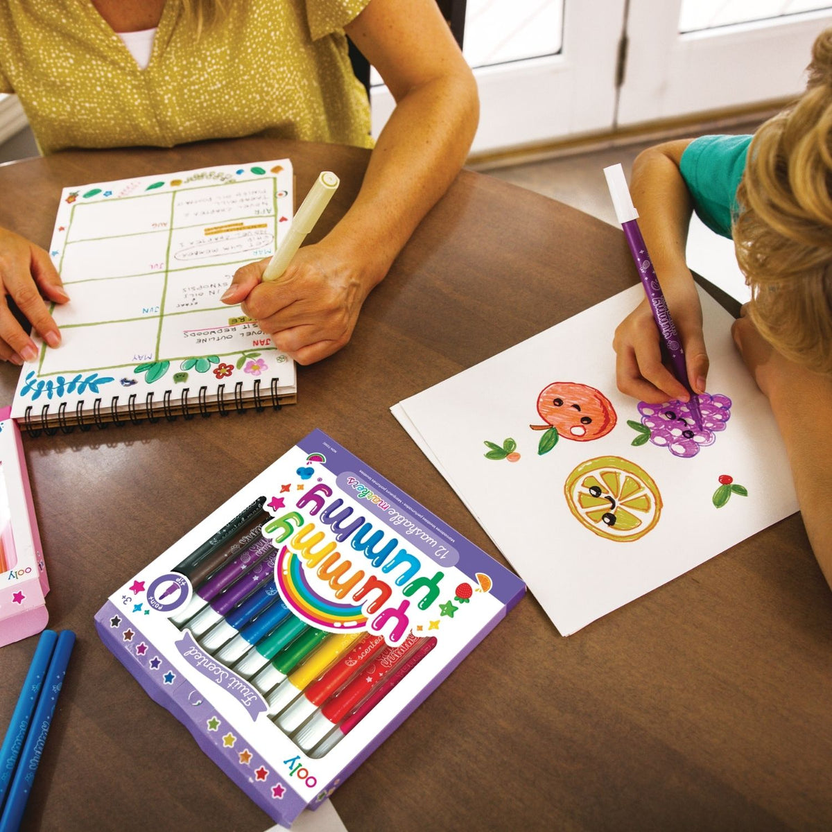 Two children sharing the pack and guessing the different fruit scents, highlighting the social and interactive value of the set.