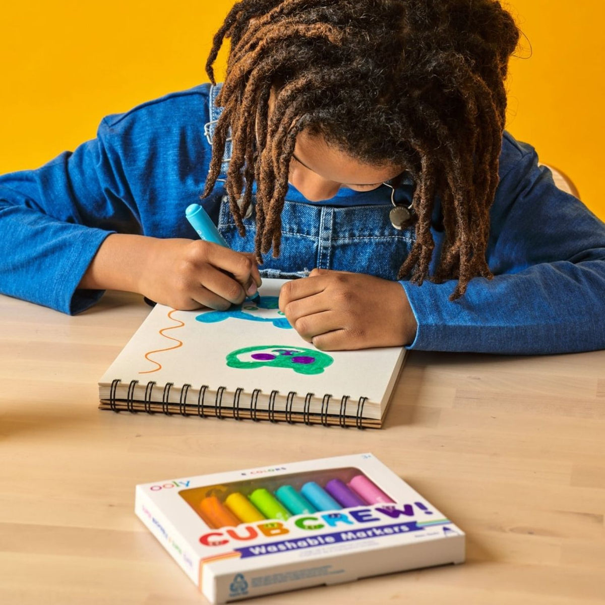 A child’s hand using the "Cubsicle Blue" marker to fill in a drawing, showing the bold, saturated ink and effortless glide across the paper.