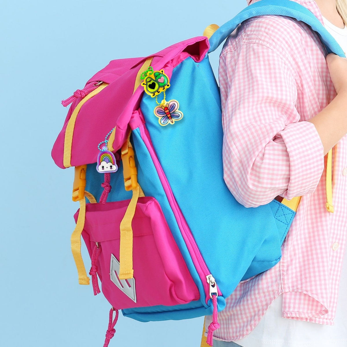 A collection of finished DIY charms, including a butterfly, avocado friends and a rainbow, attached to colourful ball chains on a school backpack.