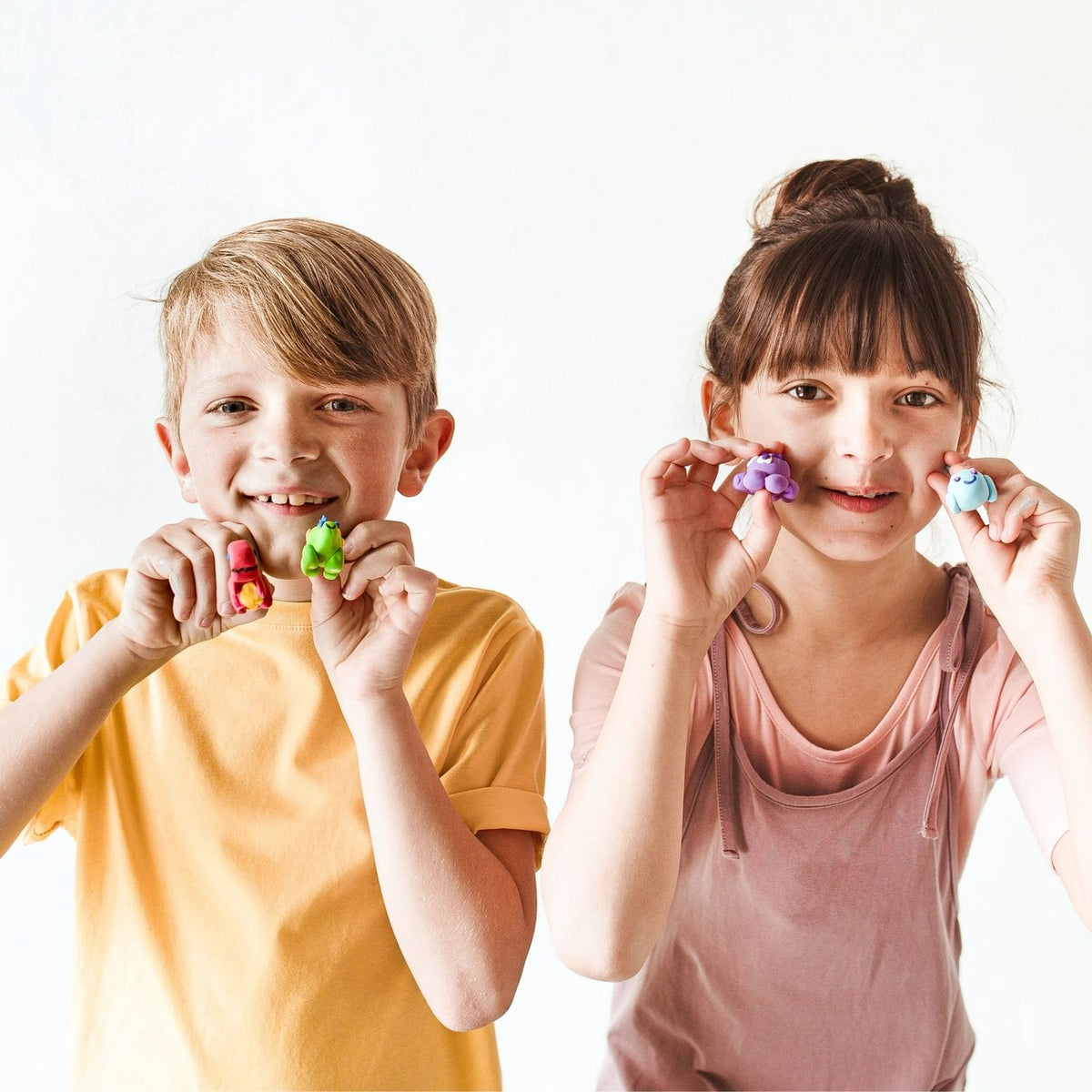 Two children holding colourful air dry clay creations including sea creatures and dinosaurs