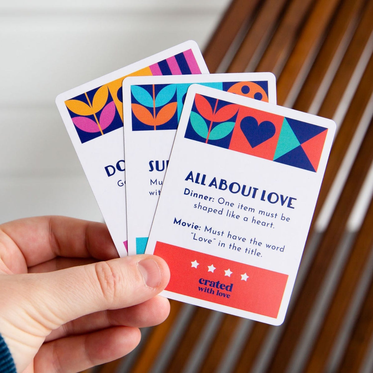 Hand holding three colorful question cards with 'All About Love' theme