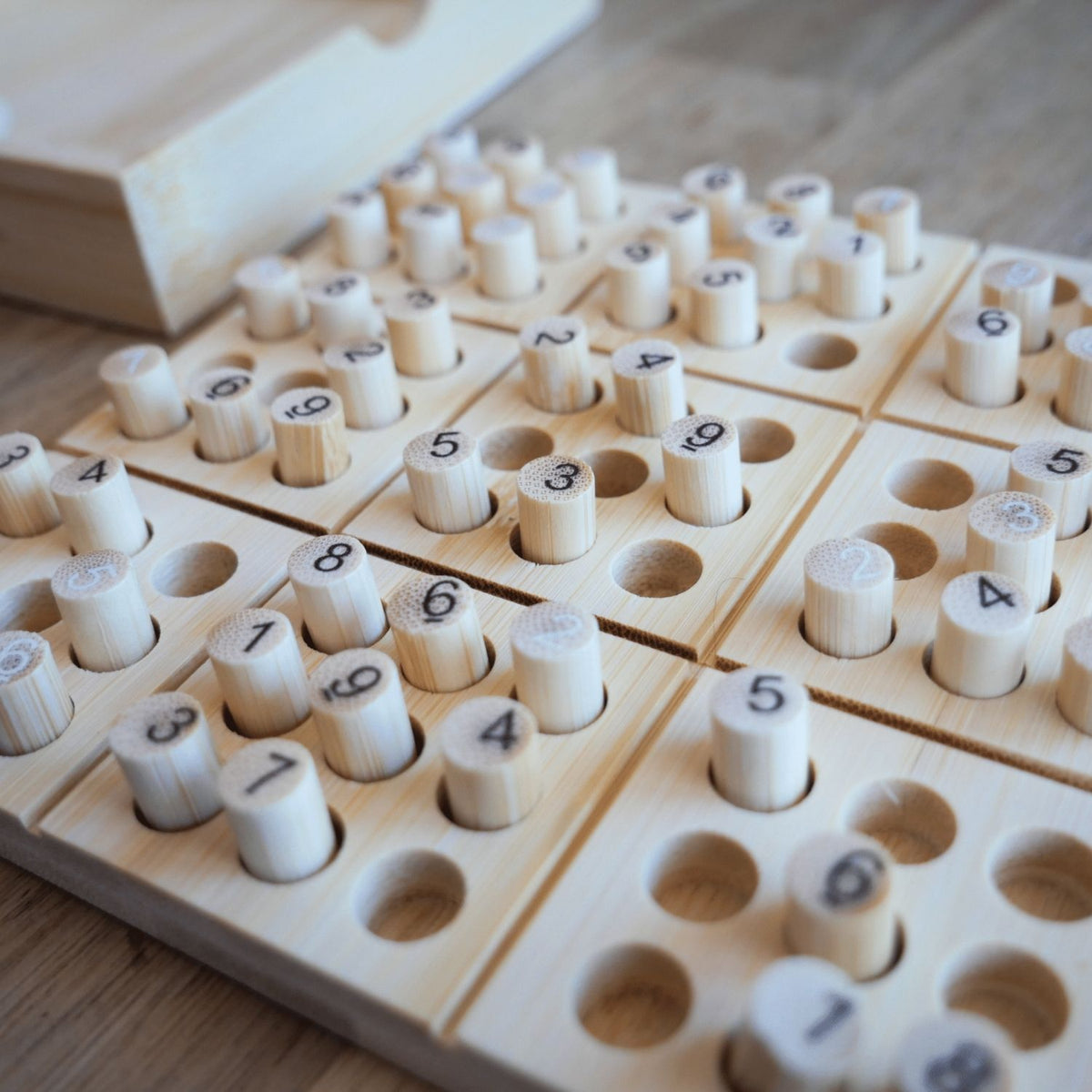 A close-up of the smooth, laser-engraved bamboo number tiles and the starter puzzle cards included with the set for ages eight and up.