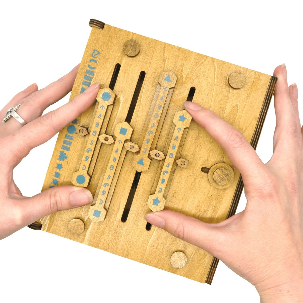 A person’s hands manipulating the wooden sliders on the front of the Codex, attempting to align the symbols to unlock the secret mechanism.