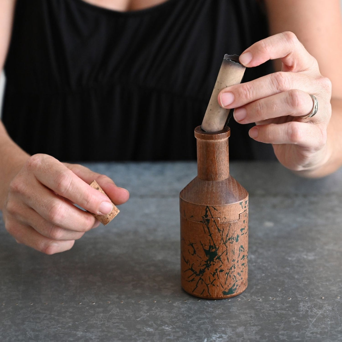 Person inserting a note into wooden bottle puzzle - unique and thoughtful gift.