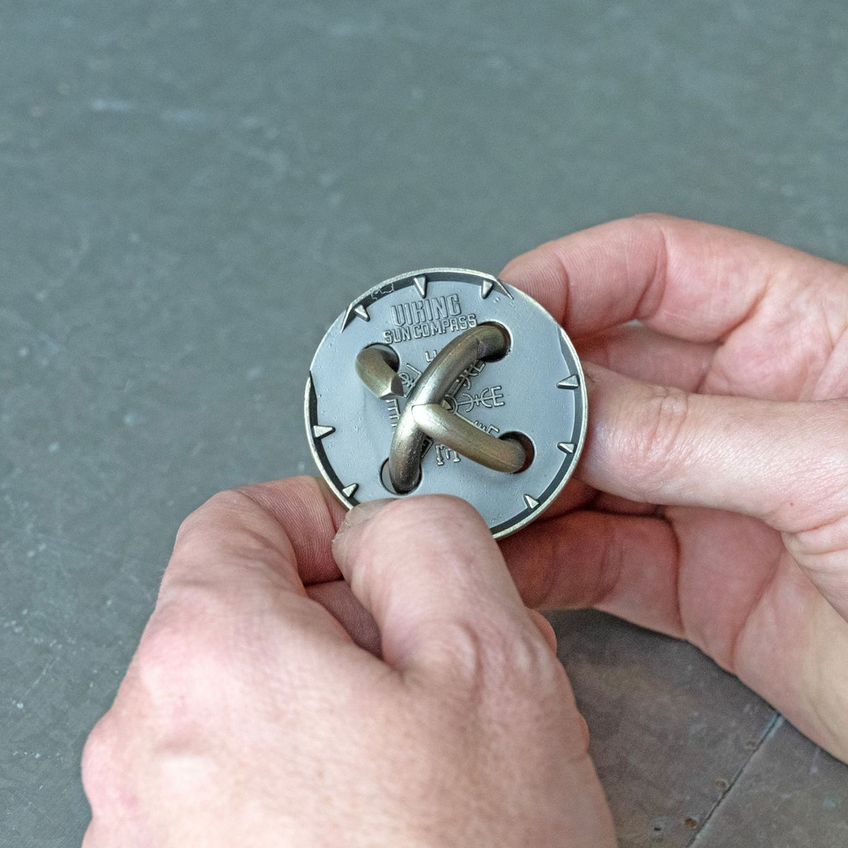 Person using a sun compass puzzle trying to release the rings in this nautical metal brainteaser for ages eight and up. 