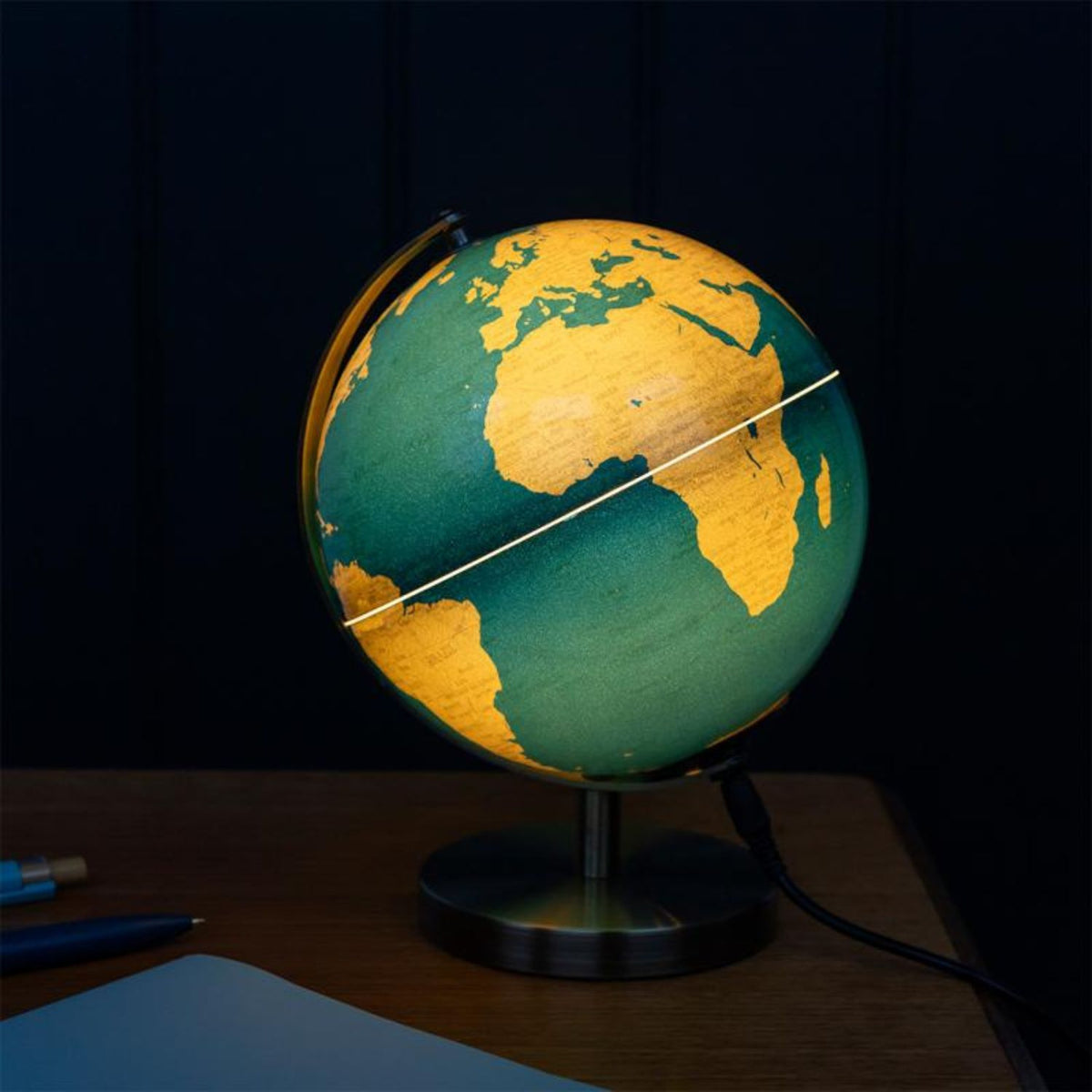 Desktop globe lamp with a dark blue ocean and gold landmasses on a metal stand. Features detailed geographical boundaries and a warm white LED glow.